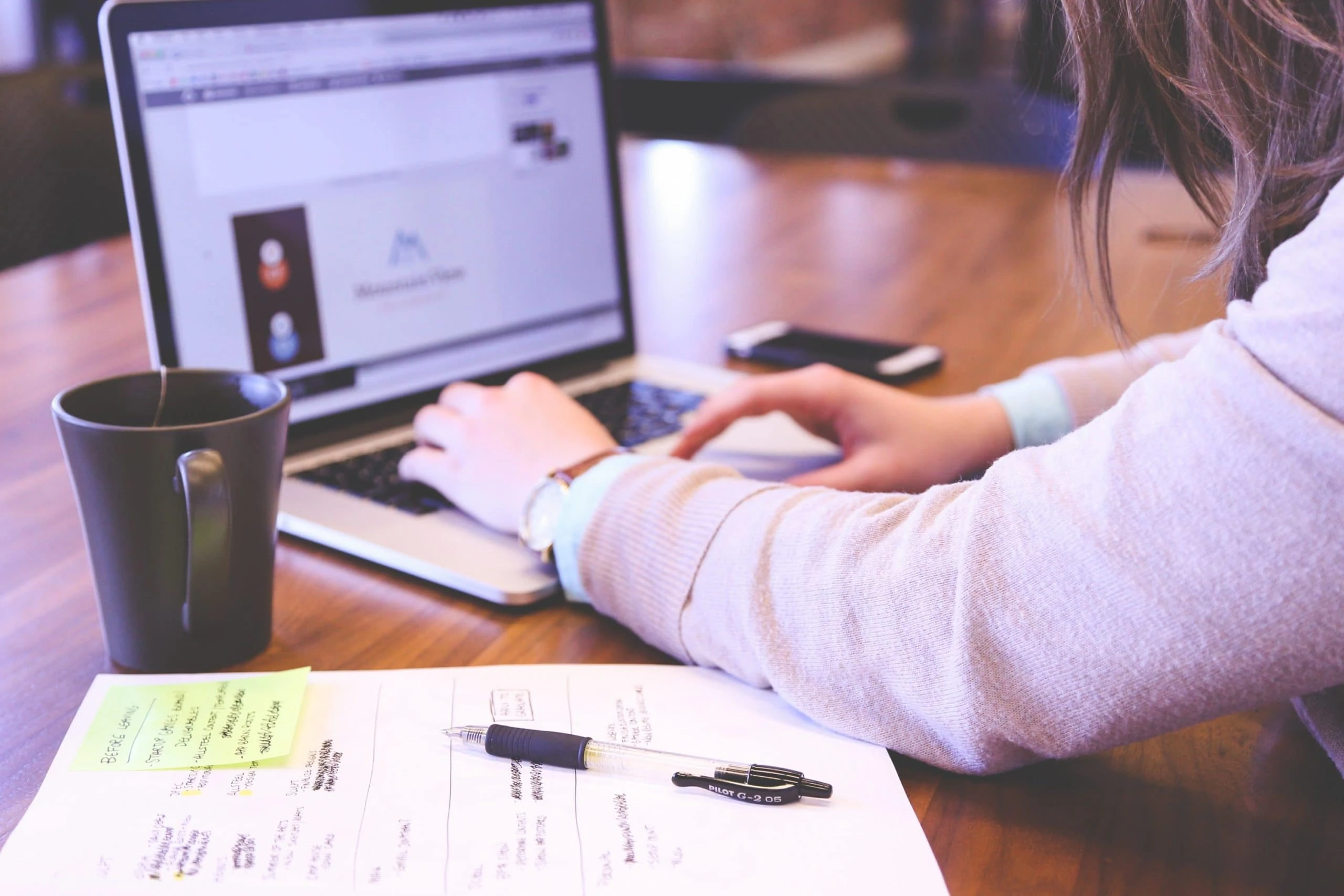 A woman optimizes content marketing strategies on a laptop at a wooden table.