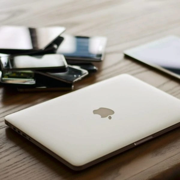 A laptop is sitting on a table next to other electronic devices ready for web design or redesign.