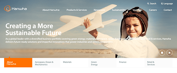 Young girl holding a paper airplane on a beach, with text about creating a sustainable future, from hanwha's website header.