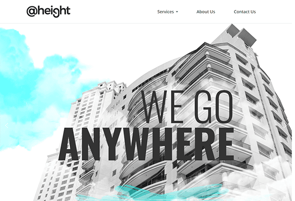 A photograph of tall modern buildings with the text "WE GO ANYWHERE" in bold capital letters. The backdrop includes a cloudy sky with blue and white hues. The @height logo is visible at the top.