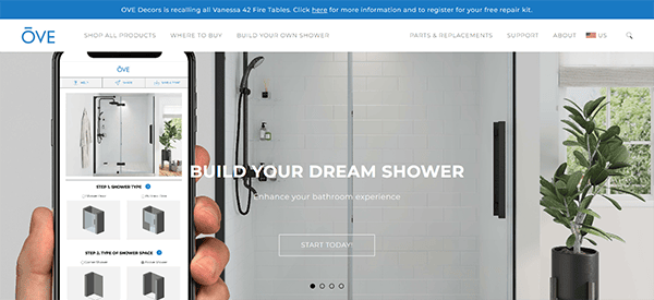 A person holding a smartphone displaying a shower design app with Ove brand website in the background, highlighting shower customization options with the text "Build Your Dream Shower.