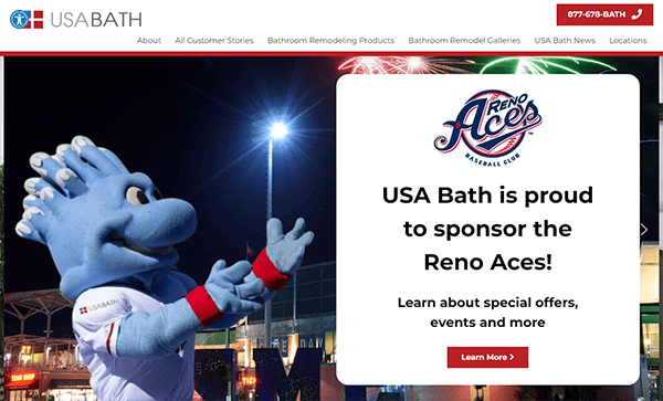 A blue mascot with a baseball glove head stands next to a sign that reads "USA Bath is proud to sponsor the Reno Aces! Learn about special offers, events, and more." Fireworks are in the background.