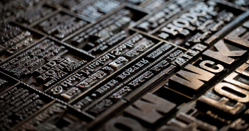 Close-up of vintage metal letterpress type arranged in rows, showcasing various letters and words in different fonts and sizes, reminiscent of the best fonts used for websites today.