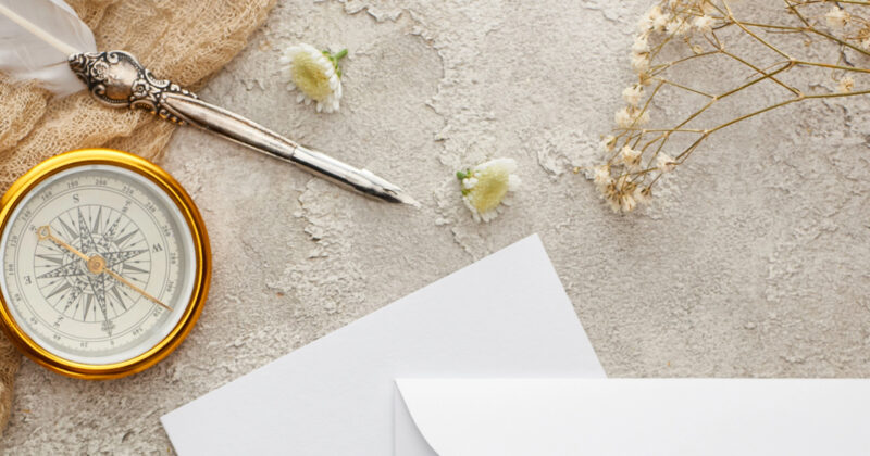Compass, quill, and dried flowers arranged near white flowers and envelopes on a textured surface evoke the meticulous planning of a therapist crafting an ultimate guide.