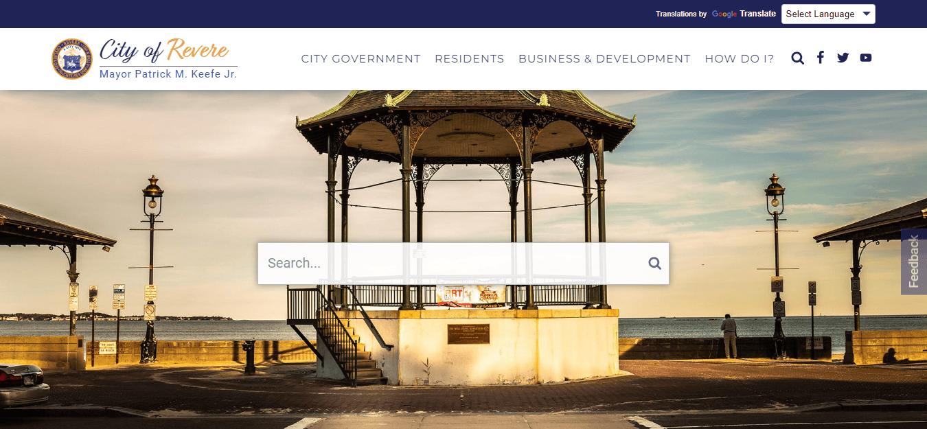 A scenic view of a gazebo on a waterfront promenade in Revere, with a search bar overlay and navigation menu at the top.