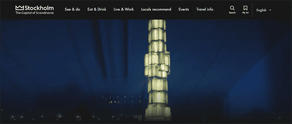 Nighttime view of a lit-up glass obelisk in Stockholm with menu options on the website header.