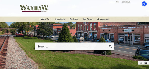 Screenshot of the Town of Waxhaw's website homepage, featuring a prominent search bar over a background image of the town's main street with stores, trees, and railroad tracks.