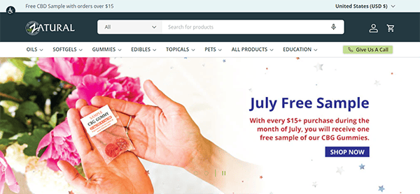 Website offering a July free sample of CBG gummies with a $15+ purchase. Image shows a hand holding a CBG gummy, surrounded by pink flowers. Various product categories like oils and gummies are listed.