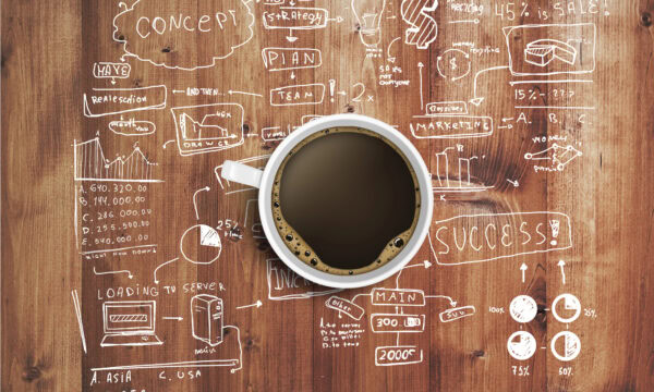 A cup of coffee on a wooden table is surrounded by various drawn business diagrams, charts, graphs, and notes—perfect for a therapist planning their SEO strategy.