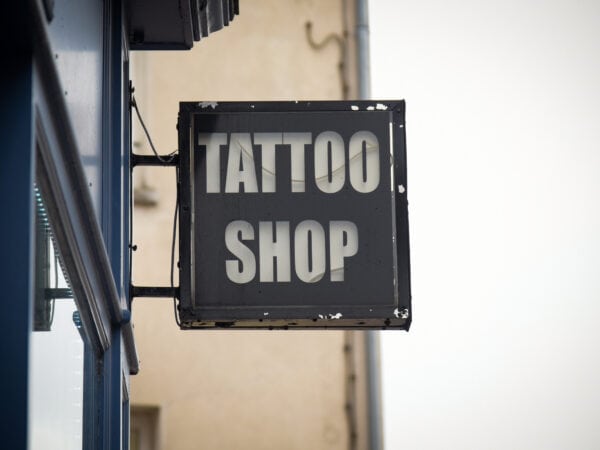 A weathered sign reading "Tattoo Shop" clings to the exterior of the building, marking one of the town's longstanding tattoo shops.