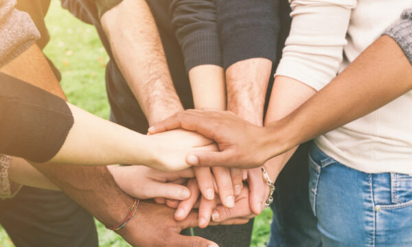 A group of therapists standing in a circle with their hands stacked in the center, symbolizing unity and teamwork.