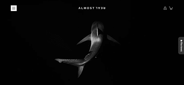 A grayscale image of a shark swimming in dark water with text reading "Almost Real" at the top. There are icons for menu, account, and cart on the sides.