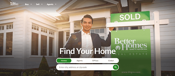 A person in a suit stands next to a "Sold" real estate sign in front of a house with the Better Homes and Gardens logo. The website asks users to find their home by entering a city, address, or zip code.