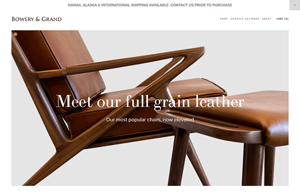 Homepage of Bowery & Grand featuring a wooden chair with leather upholstery, and text promoting their full grain leather products. Navigation menu includes links to shop, contact, and cart.