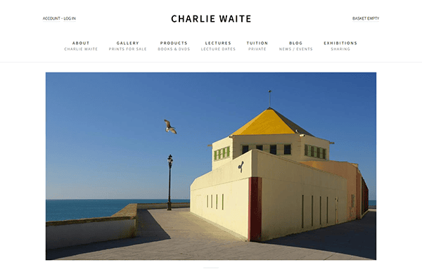 A coastal building with a yellow pyramid-shaped roof is shown under a clear blue sky, with a seagull flying nearby.