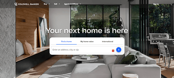 A living room with modern furniture, floor-to-ceiling windows, and a search bar overlay displaying Realtor websites options. Text reads "Your next home is here." with the Coldwell Banker logo.
