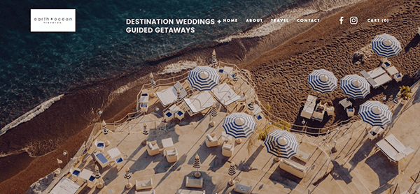 Aerial view of a beachside area with striped umbrellas, loungers, and a sandy shore. Website header features navigation links for the best travel agency specializing in destination weddings and guided getaways.