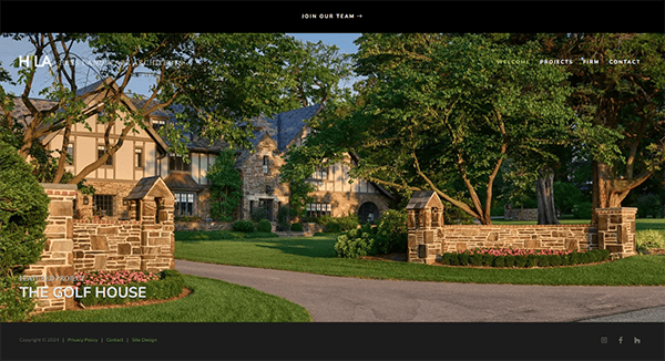 A stately stone building with lush landscaping and large trees, identified as "The Golf House," set against a bright, clear sky. A stone entrance gate is visible in the foreground.