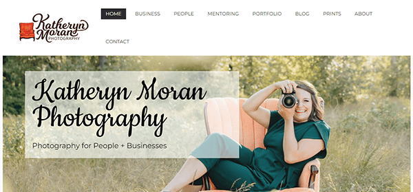 The homepage of Katheryn Moran Photography's website featuring a woman in green holding a camera while sitting in an orange chair in a grassy outdoor setting.