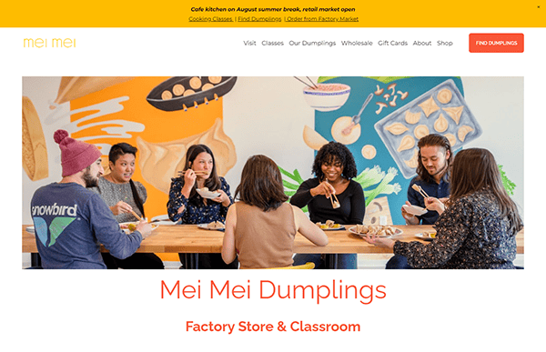 A group of people sit together at a wooden table making dumplings. The wall behind them is decorated with colorful murals of dumplings and ingredients. Text reads "Mei Mei Dumplings Factory Store & Classroom.