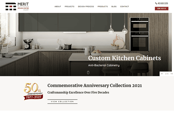 Modern kitchen display featuring sleek, custom cabinets and a 50th Anniversary promotional banner for a company named Merit Kitchens, highlighting craftsmanship excellence over five decades.