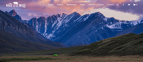 A vibrant website banner showing a mountainous landscape at dusk with layered peaks, a small green tent in the grassy foreground, and navigation links at the top.