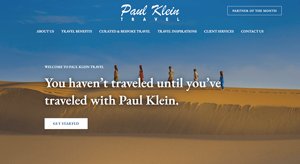 Screenshot of the Paul Klein Travel website homepage, featuring a desert landscape with a group of people walking on sand dunes and a central call-to-action message: "You haven’t traveled until you’ve traveled with Paul Klein.