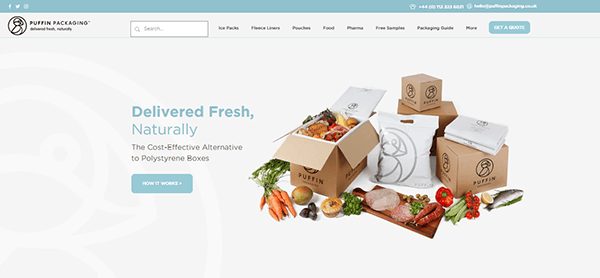 Website homepage of Puffin Packaging displaying eco-friendly packaging for fresh produce including fruits, vegetables, and seafood inside cardboard boxes. Features tagline "Delivered Fresh, Naturally.