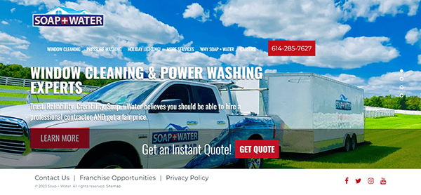 A Soap + Water truck and trailer in a grassy field under a blue sky. Text reads, "Window Cleaning & Power Washing Experts" and offers services with contact information and options to learn more or get a quote.