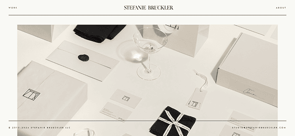 A neatly arranged collection of branded white stationery and packaging, including envelopes, gift tags, business cards, and a wine glass on a white surface.