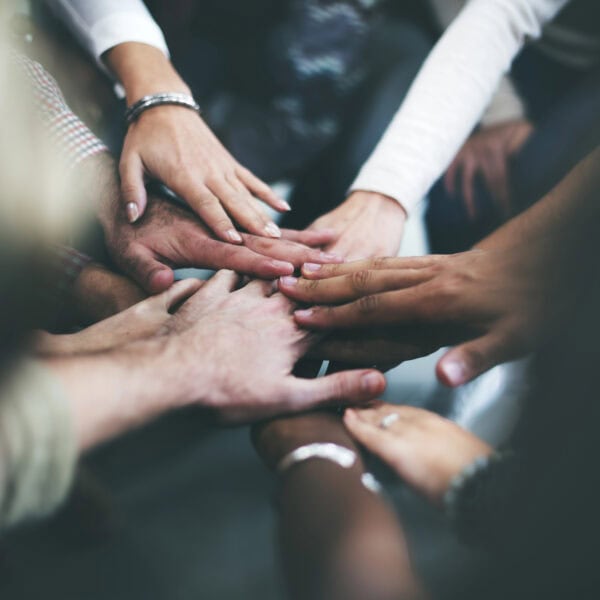 A group of people places their hands together in the center, showcasing unity and teamwork, demonstrating a commitment to ADA Compliance.