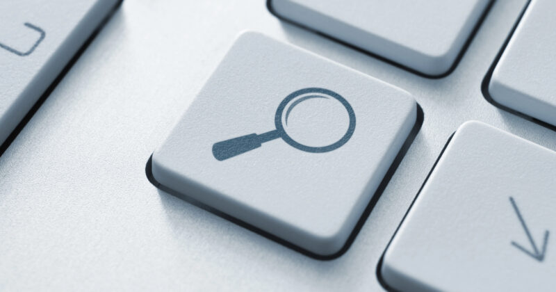 Close-up of a keyboard key with a magnifying glass icon, typically representing search functionality, often crucial when addressing Google search issues or fixing website visibility problems.