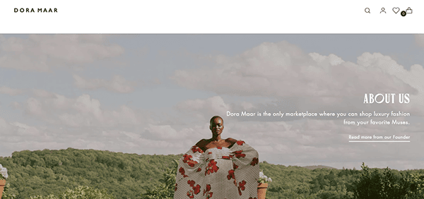 A person stands outdoors in a field, wearing a floral dress. Text on the right side says "About Us" with information about Dora Maar and a link to read more from the founder.