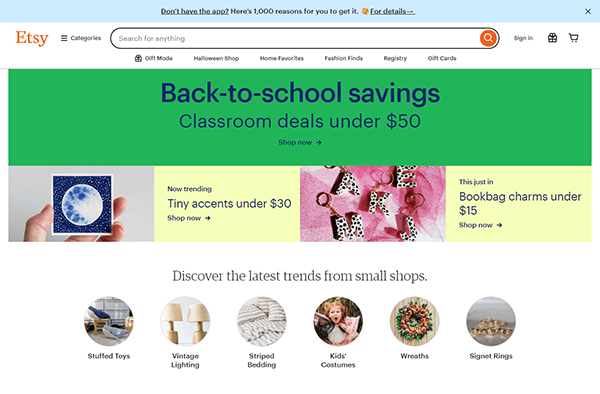 Etsy homepage displaying back-to-school savings, classroom deals under $50, and trending items such as tiny accents and bookbag charms. Various shop categories are featured below.