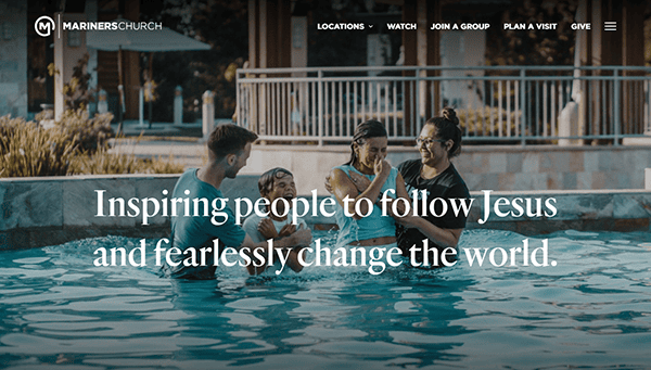 Four people standing in a pool. A child in the center is being baptized. Text overlay reads, "Inspiring people to follow Jesus and fearlessly change the world." Church website menu is visible.