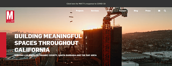 Construction site at sunset with a prominent building under construction and a crane. The text reads, "BUILDING MEANINGFUL SPACES THROUGHOUT CALIFORNIA". Links for Projects, Services, Careers, Blog, and Press are visible.