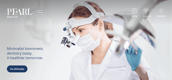 Dentist wearing magnifying loupes and mask works on a patient. Text reads: "Minimalist biomimetic dentistry today. A healthier tomorrow. Our philosophy." Pearl Dental NYC branding and navigation links.