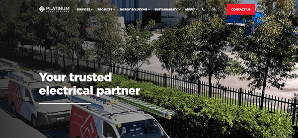 Several service vans with ladders on rooftops are parked along a fence, promoting services of a company named "Platinum Electricians." The text overlay reads "Your trusted electrical partner.