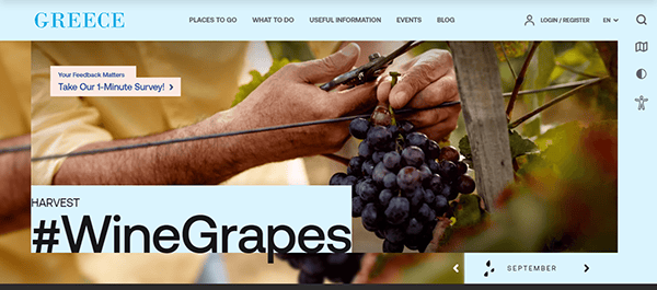 Person cutting a cluster of wine grapes from a vine. The header reads "GREECE" and a hashtag "WineGrapes" is displayed. There are navigation links at the top and a survey prompt on the left.