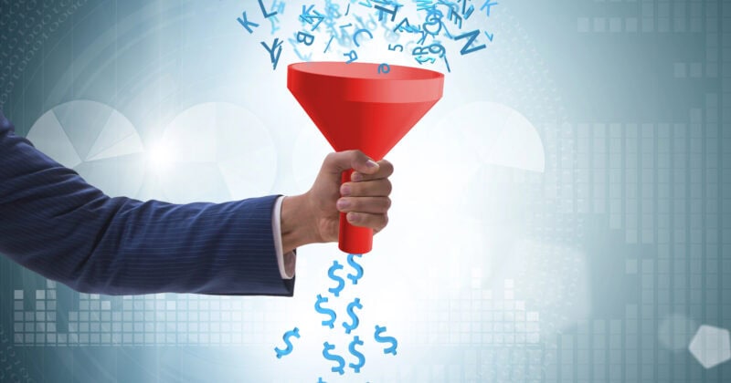 A hand holding a red funnel filters letters at the top into dollar signs at the bottom, symbolizing data conversion to money, much like Smart Bidding Strategies transform SEO keywords into financial success.