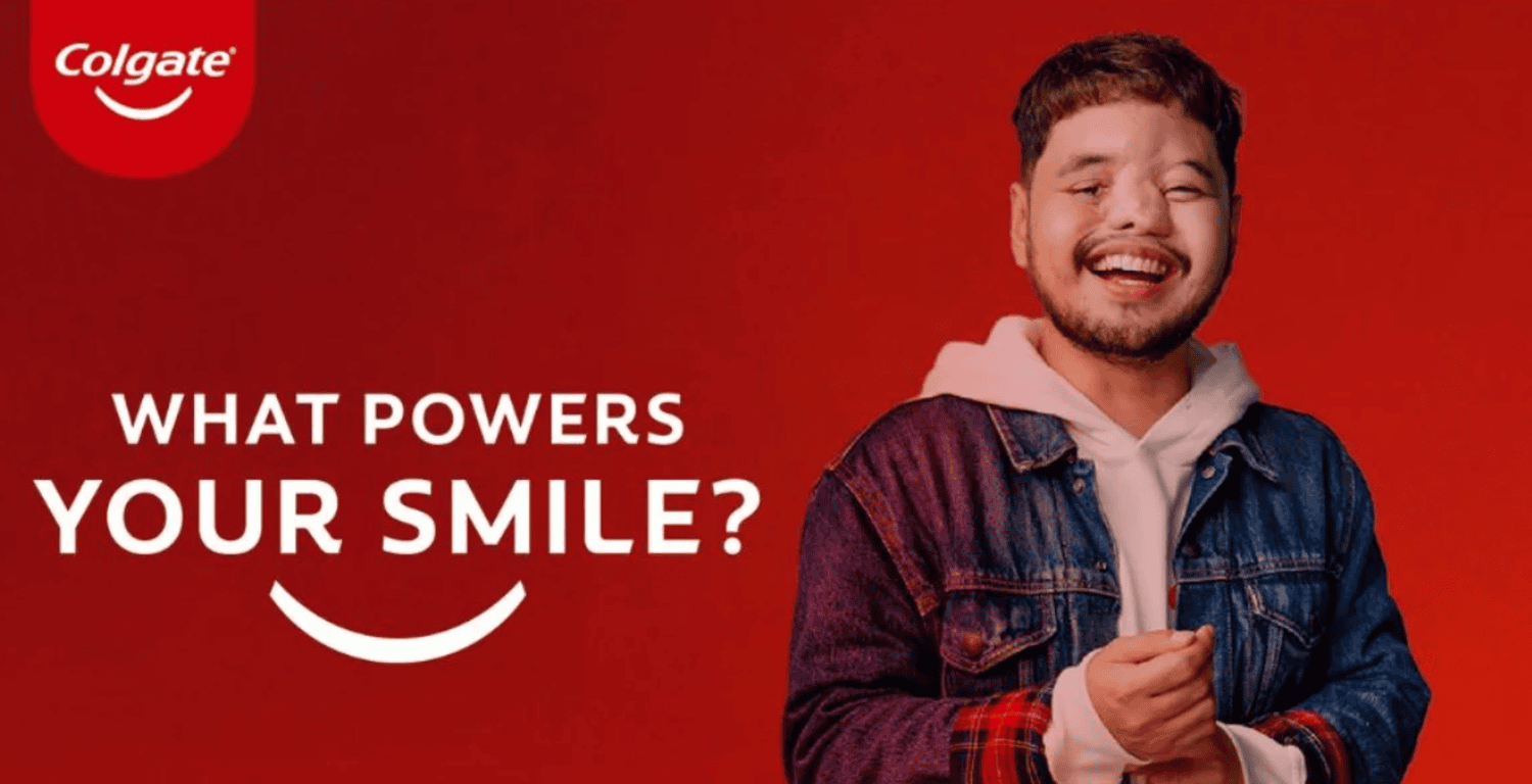 A person smiling against a red background with the Colgate logo. Text reads, "What powers your smile?" Discover how winning examples of social media ads maximize ROI for your dental care.