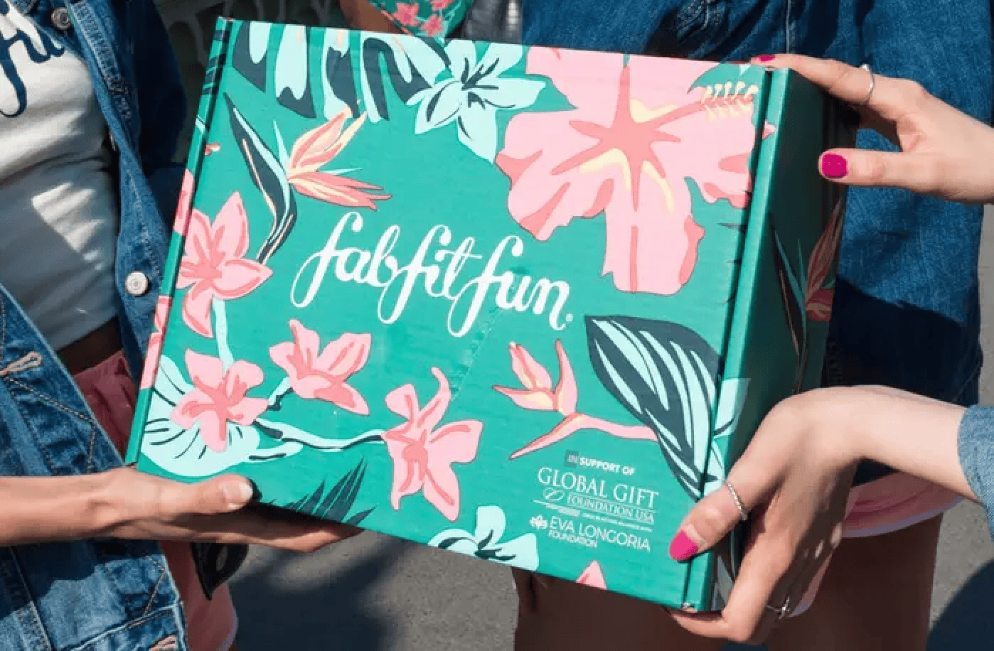 Three people hold a colorful FabFitFun box adorned with floral designs, while Eva Longoria's name graces the bottom. This image is a winning example of how social media ads can generate massive ROI by leveraging celebrity endorsements and vibrant visuals.