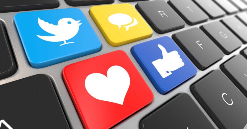 Keyboard with four colorful keys featuring icons: a blue bird, yellow speech bubble, red heart, and blue thumbs-up symbol—perfect for creating winning examples in social media ads.