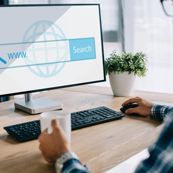 A man uses a computer, the screen showing a Google Local Service Ads search bar. A plant sits quietly on the desk, adding a touch of nature to his Ads Management workspace.