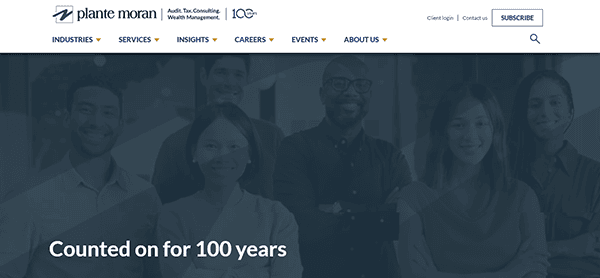 A group of diverse individuals stands proudly in front of a "Plante Moran" banner, showcasing the text "Counted on for 100 years," epitomizing what makes it one of the best accounting firm websites today.