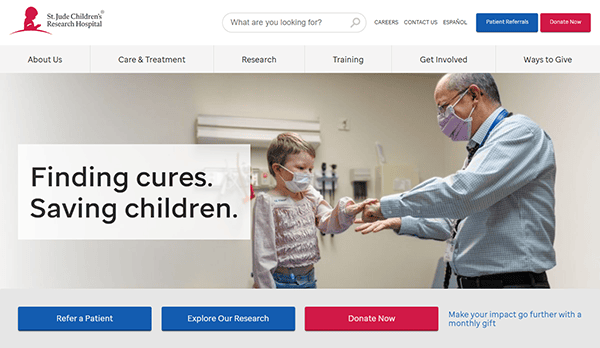 A man and child in masks at a medical facility stand beneath a banner proclaiming, "Finding cures. Saving children," accompanied by the St. Jude Children's Research Hospital logo, embodying one of the best charities dedicated to healing and hope.