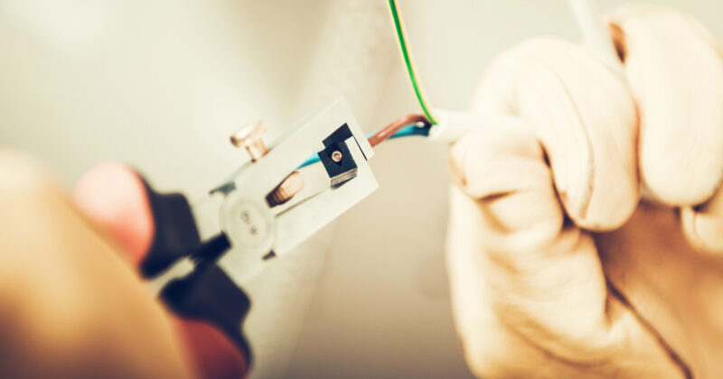 Hands expertly wielding a wire stripper, effortlessly removing insulation from electrical wires—a perfect snapshot for commercial electrician websites.