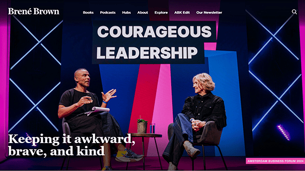 Two individuals sit on stage discussing "Courageous Leadership" amidst a backdrop of vibrant lighting. Text reads, "Keeping it awkward, brave, and kind—an approach applauded by the creators of the 20 Best Author Websites.