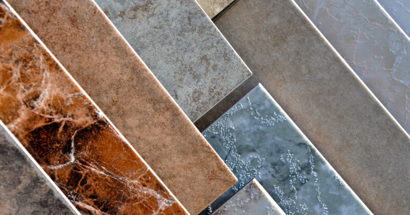 A selection of rectangular ceramic tiles in various colors and marble-like patterns, arranged diagonally in overlapping layers and inspired by designs from the top tile sites.